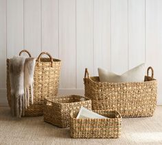 three woven baskets sitting on the floor next to each other with towels hanging from them