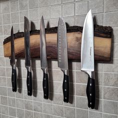 five knives are hanging on a wall with a wooden handle and knife holder attached to it