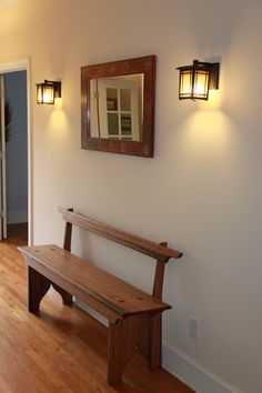 a wooden bench sitting next to a wall with two lights on it's sides