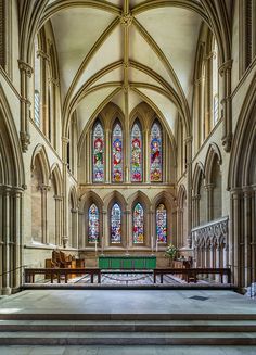 the interior of a church with stained glass windows and pews on either side of the alter