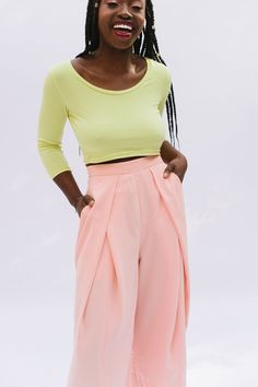 a woman standing with her hands on her hips wearing wide legged pink pants and a yellow top