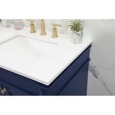 a white sink sitting on top of a blue cabinet next to a plant in a vase