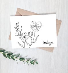 thank you card with black and white flowers on it next to a green leafy branch