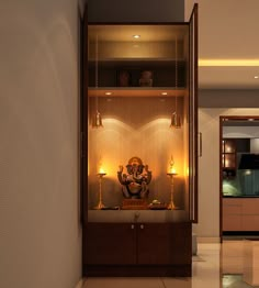 an open cabinet in the middle of a room with lights on it and a buddha statue inside