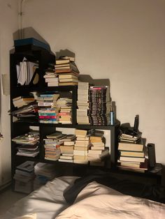 a book shelf filled with books next to a bed