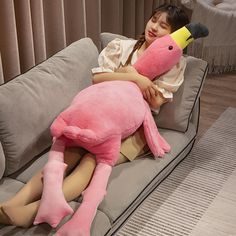 a woman laying on top of a couch holding a pink stuffed animal