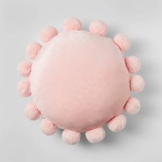 a pink round pillow with pom - poms on the top and bottom half