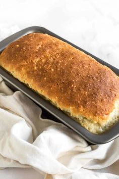 a loaf of bread sitting on top of a baking pan next to a white towel