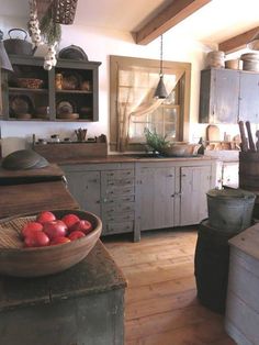 an old fashioned kitchen with wooden floors and white cupboards, wood flooring, and large bowl of fruit on the counter