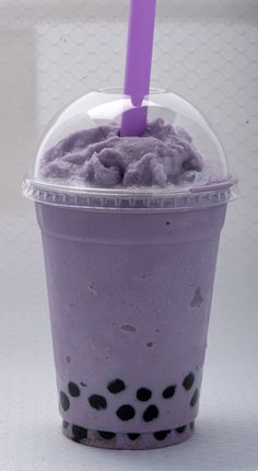 a purple drink with black spots on the rim and a purple straw sticking out of it