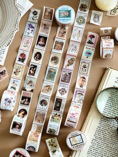 many different stamps on a table next to a magnifying glass and an open book