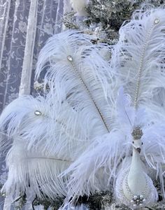 a white christmas tree decorated with feathers and ornaments