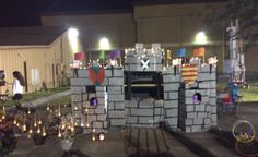 a group of people standing around a building made out of blocks and bricks at night