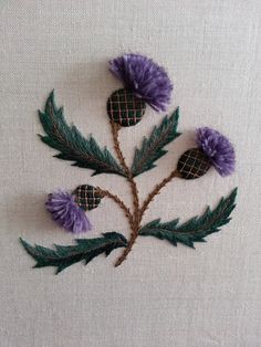 a close up of a flower on a piece of cloth with green leaves and purple flowers