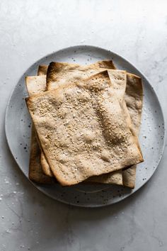 three pita breads on a plate with some seasoning sprinkles