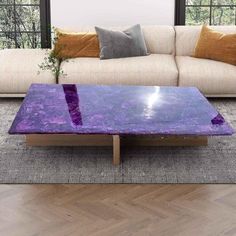 a purple coffee table sitting on top of a wooden floor next to a white couch