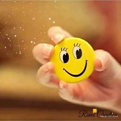 a hand holding a yellow smiley face ball