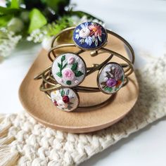 three bracelets with flowers on them sitting on a plate