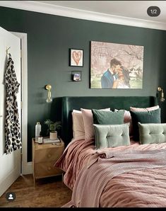 a bedroom decorated in green and pink with pictures on the wall above the headboard