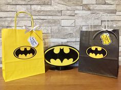 two bags with batman logos on them sitting next to each other in front of a brick wall