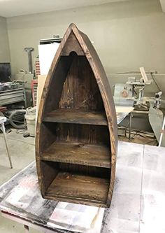 a boat shaped shelf sitting on top of a table in a room filled with tools