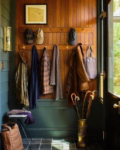 a coat rack with hats and umbrellas hanging on the wall next to a door