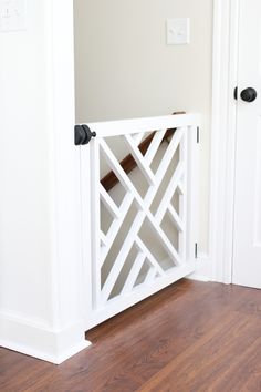 a room with white walls and wooden flooring next to an open door that has a black handle on it