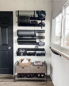 a black door and some shelves with items on them in a room that has wood flooring