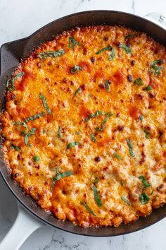 a cheesy pizza in a cast iron skillet on a marble countertop