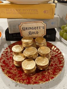 a plate with gold coins sitting on top of it next to some books and bowls