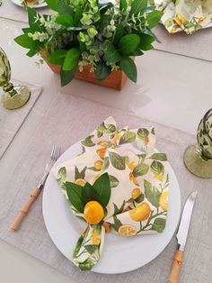 a white plate topped with an orange and green napkin next to a potted plant