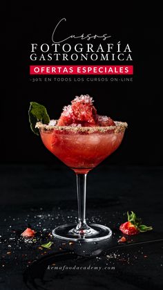 a red cocktail in a coupe glass with garnishes on the rim and green leaves