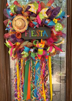 a colorful wreath that says fiesta hanging on the front door with ribbons and straw hats