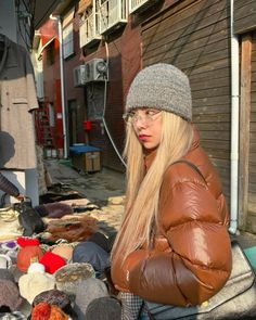 a woman sitting on the ground in front of a pile of hats