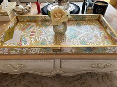 an ornately decorated coffee table with flowers on the tray and other items around it