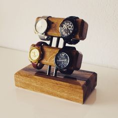 three watches are stacked on top of each other in a wooden display stand with white walls behind them