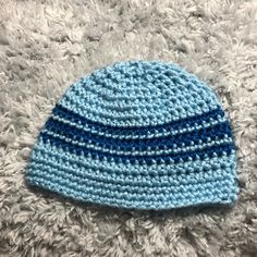 a blue and white crocheted hat laying on top of a rug