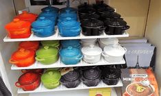 the shelves are filled with different colored pots and pans