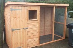 a large wooden shed sitting next to a trash can