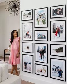 a woman standing next to a wall with pictures on it