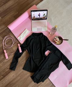 a woman's workout outfit and laptop on a yoga mat next to a pink towel