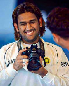 a man holding a camera and smiling at another person with a smile on his face