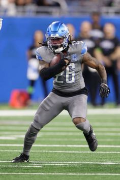 a football player running with the ball in his hand and people watching from the stands