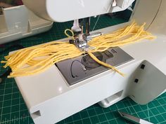 a close up of a sewing machine with yellow yarn on the front and side of it