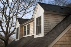 the roof of a house with two windows and a shingled dormer on it