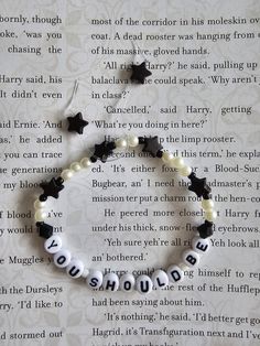 a beaded bracelet with black and white beads that spell out the word should you be married?