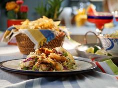 a plate full of food sitting on top of a table next to a basket filled with chips