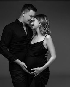 a pregnant couple cuddles in black and white for their portrait session at the studio