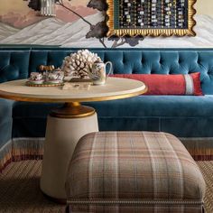 a living room with a blue couch and coffee table in front of a painting on the wall