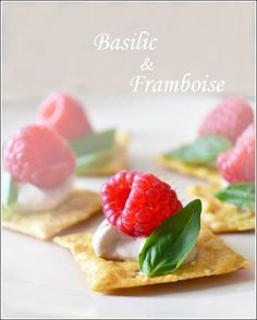 small crackers with raspberries and cream on them are sitting on a plate